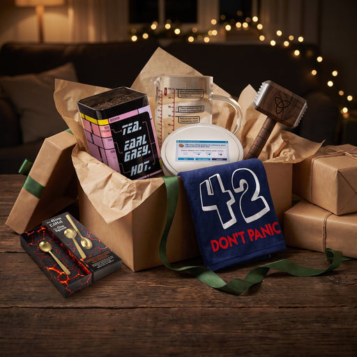 Nerd-Geschenk-Set: geöffnete Geschenkbox mit Teedose, Messbecher, Keksdose, Mjölnir-Fleischhammer, Badehandtuch 42 und Der EINE Löffel
